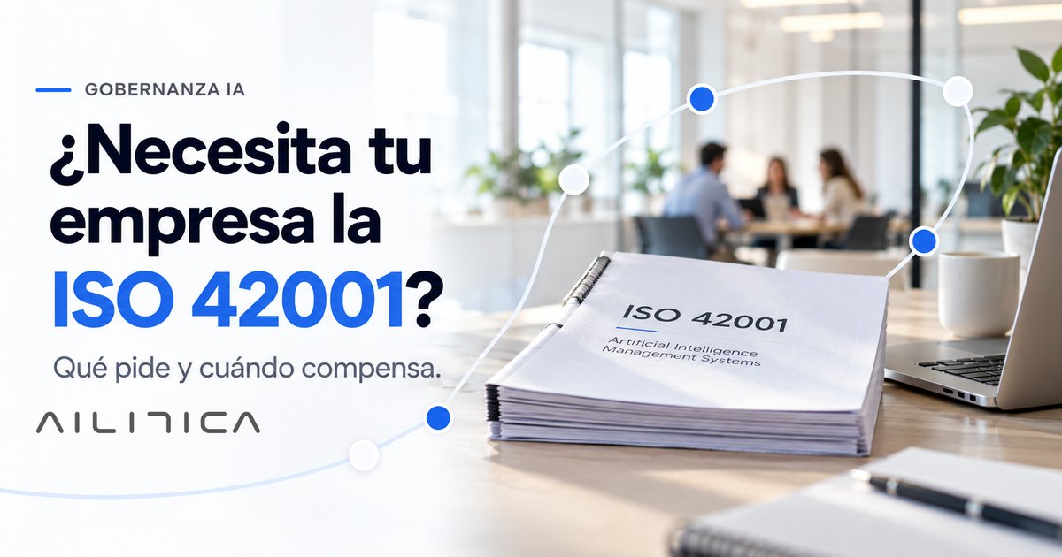 Un ejemplar impreso de la norma ISO 42001 sobre una mesa de oficina, junto a un portátil, con una reunión desenfocada al fondo
